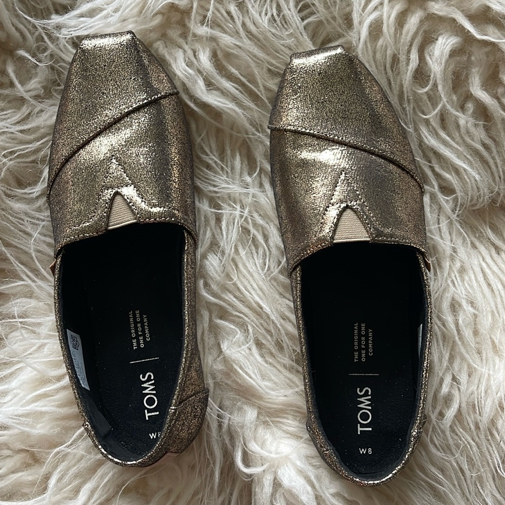 Tom’s size 8 gold slip ons.